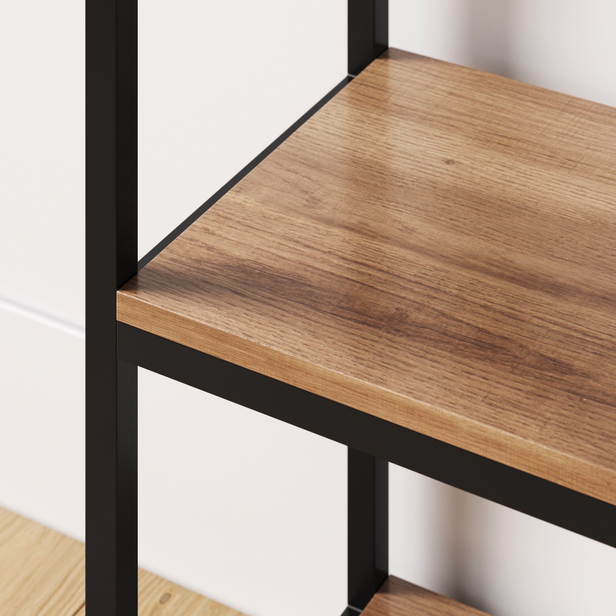 Close-up of a wooden shelf with a smooth surface and black metal frame, set against a white wall and light-colored wooden floor.