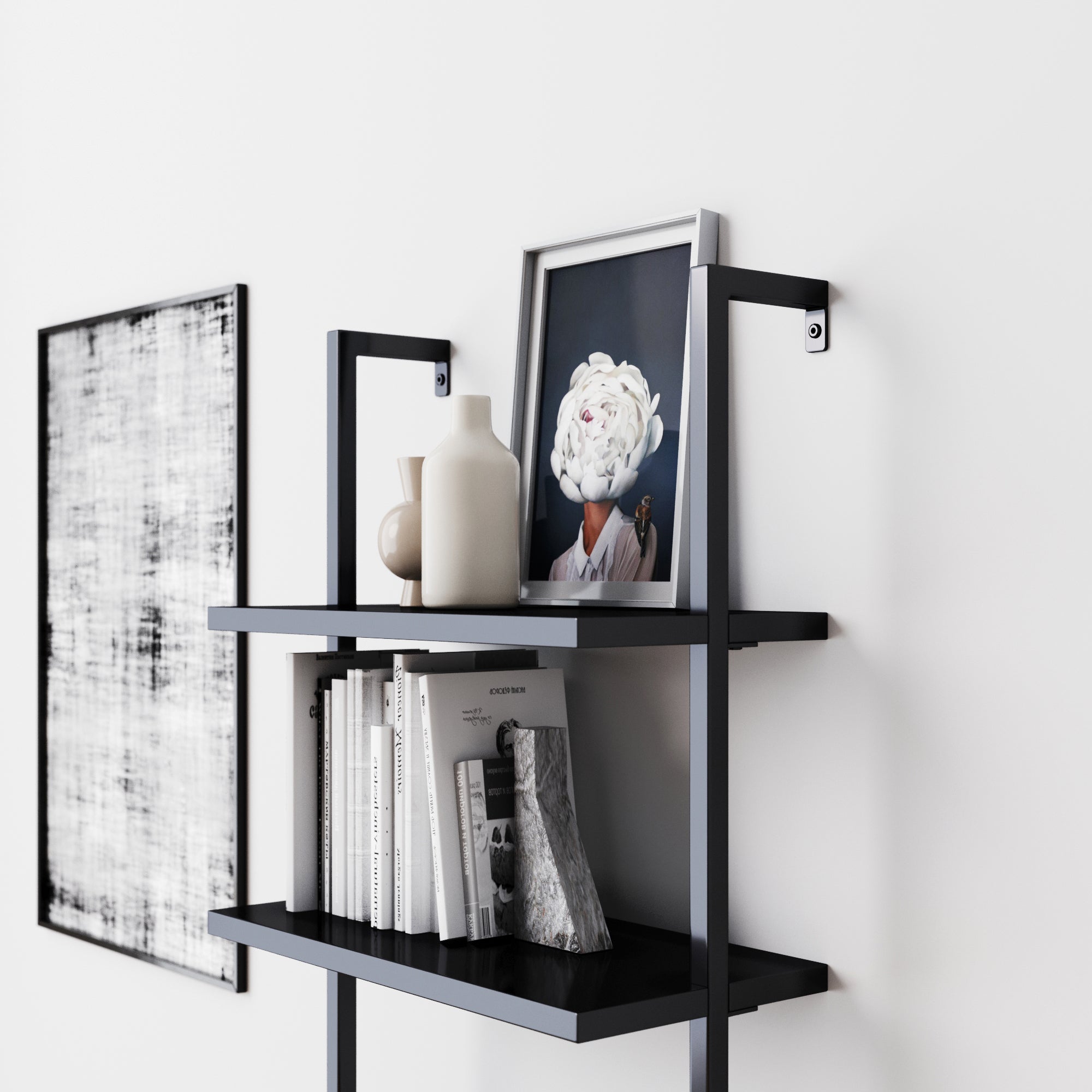 A modern black metal wall shelf holds books, neutral-toned vases, and a framed portrait of a person with a white flower for a face; abstract black and white art hangs on the adjacent white wall.