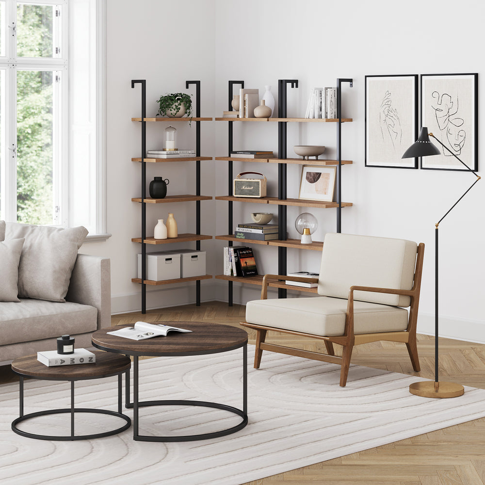 A living room featuring a corner bookshelf with decor, two nesting coffee tables, and an upholstered armchair next to a floor lamp.