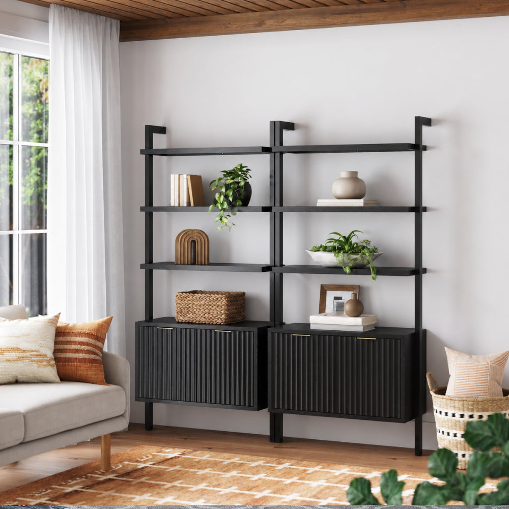 Two black wall-mounted shelving units with closed storage cabinets at the base, decorated with books, plants, and decor items.