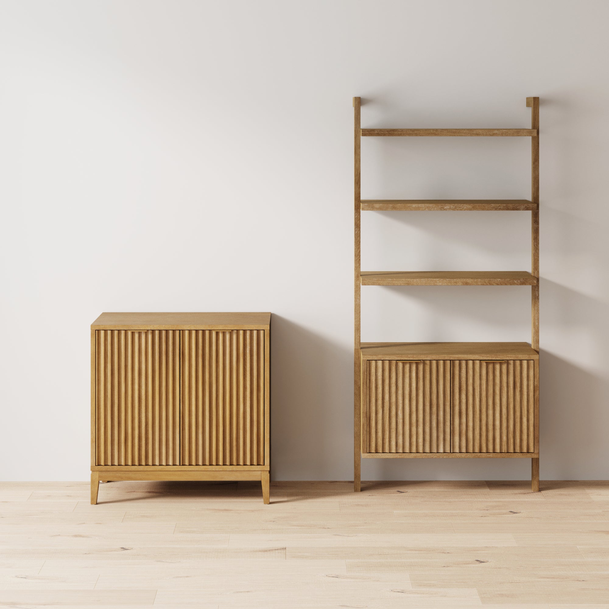 Minimalist interior with light wooden flooring, featuring a small wooden cabinet with vertical grooves on the left and a matching tall shelving unit with four open shelves and a closed cabinet at the bottom on the right.