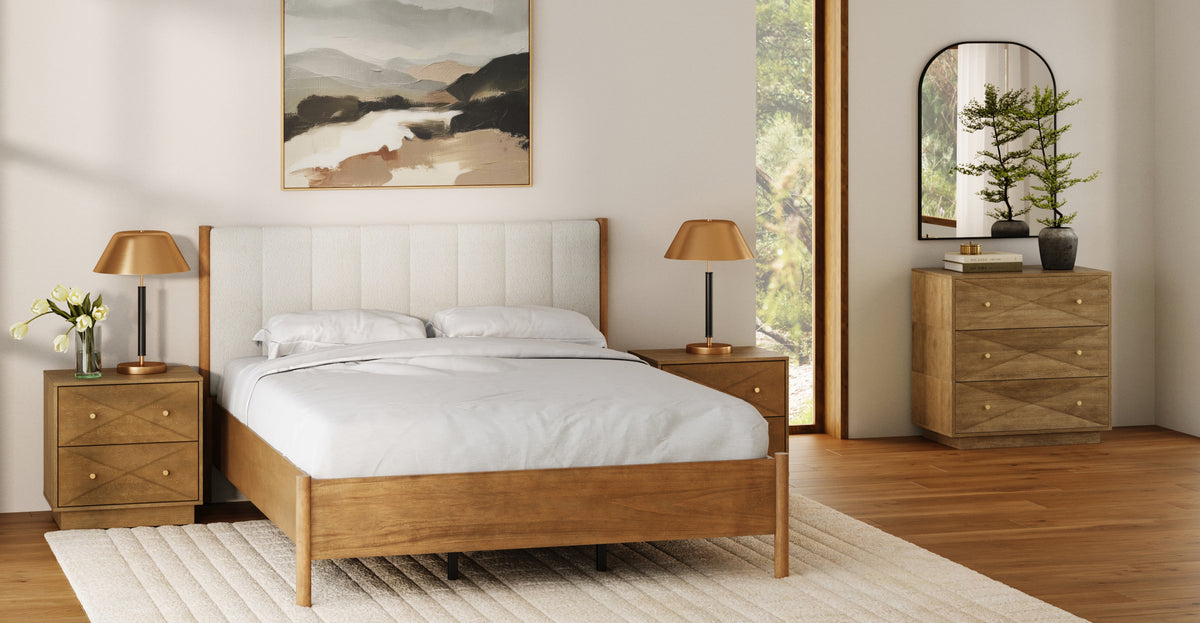 A bedroom featuring a wooden bed with an upholstered headboard, two wooden nightstands with gold-toned lamps, and a matching wooden dresser with an arched mirror above it.