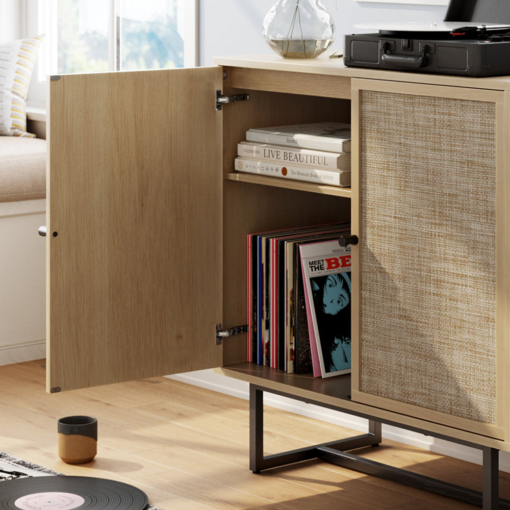 Light wood media console with a cane-paneled door, open to reveal shelves holding books and vinyl records, with a turntable resting on top.