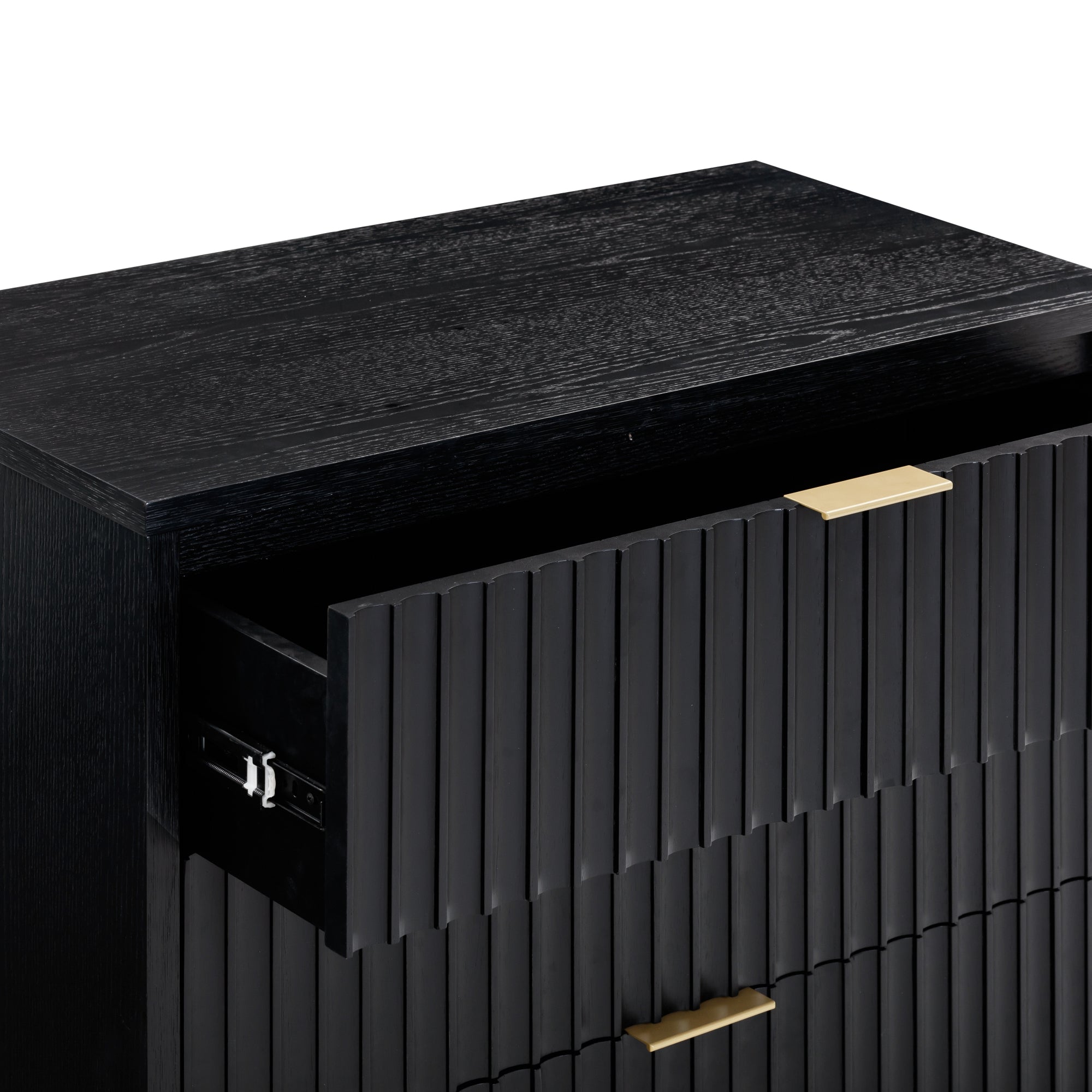 A close-up of a modern black dresser with a textured front panel, featuring brass handles. The top drawer is partially open, revealing metal drawer slides inside.