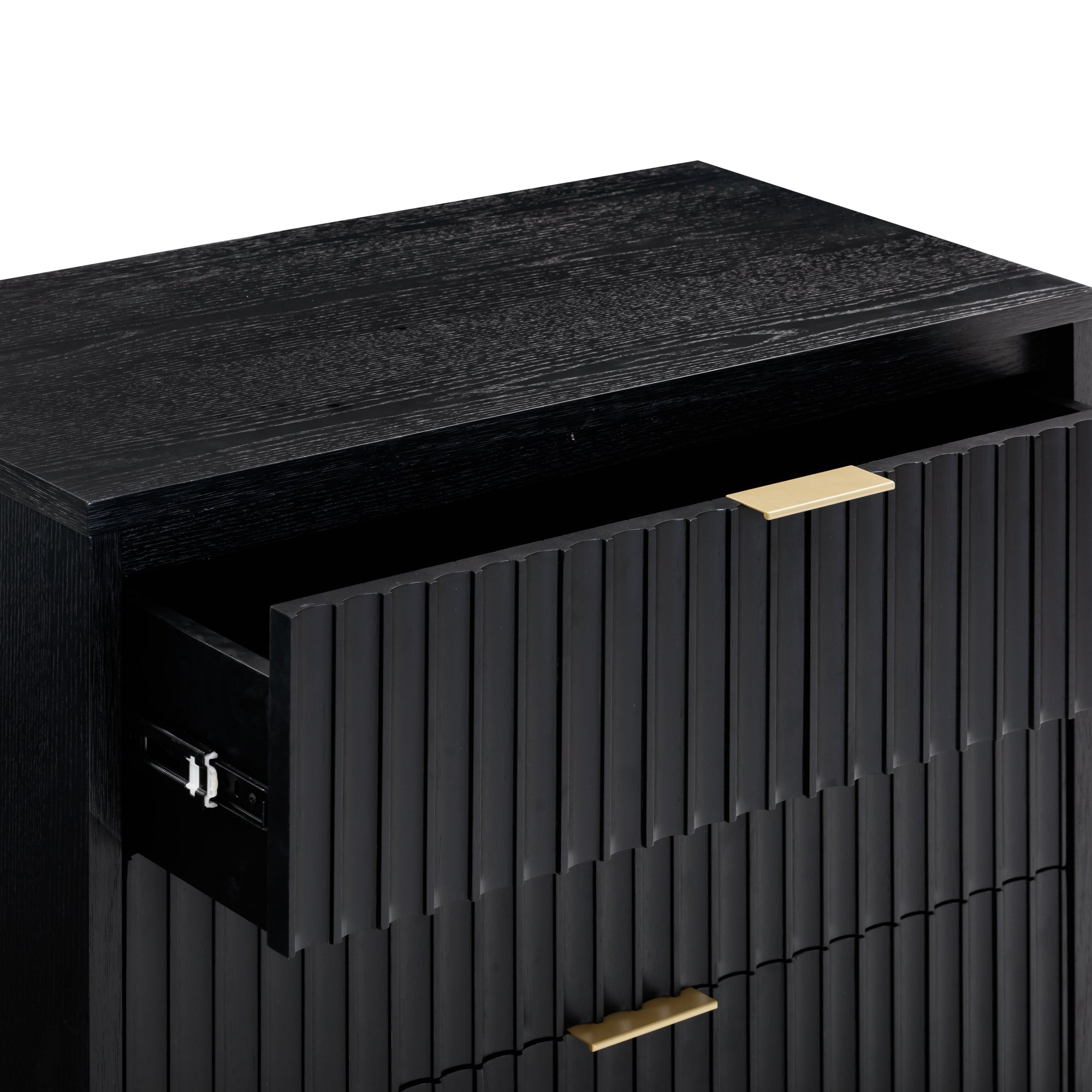A close-up of a black wooden dresser with a partially open top drawer. The dresser features vertical grooves and gold rectangular handles. The surface and texture of the wood are visible.