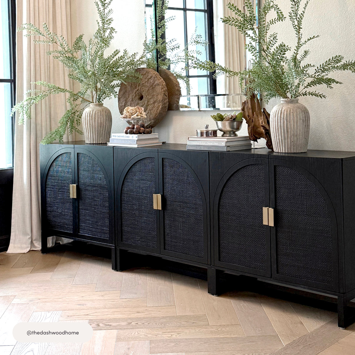 Nathan James Arched Wooden 2-Door Storage Cabinet Black Rattan featuring three arched door cabinets with rattan panels and gold handles, topped with decorative vases and books.