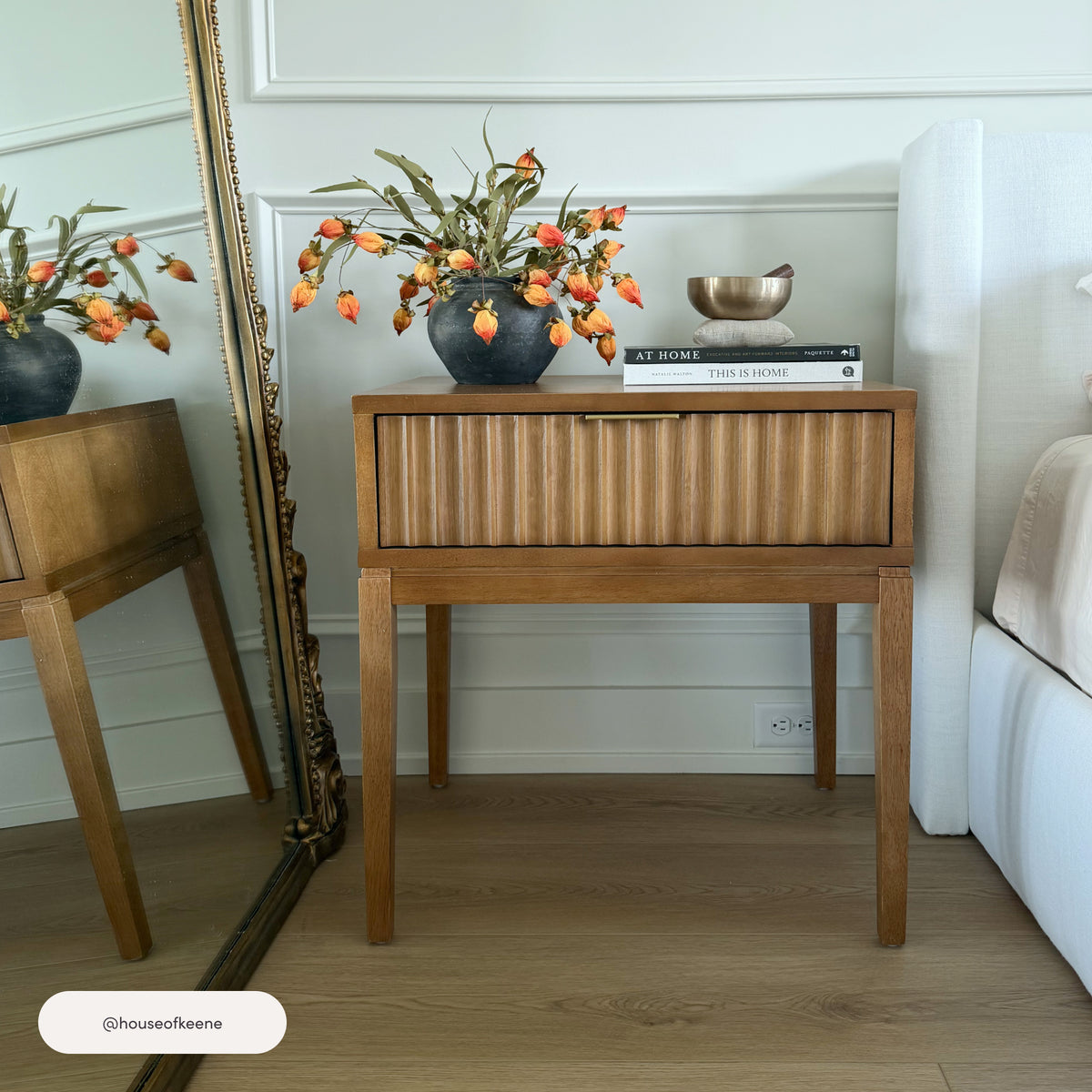 Nathan James Bohemian Wood Nightstand with Drawer in light brown, featuring a single fluted drawer topped with a vase of orange flowers, a small bowl, and two books.