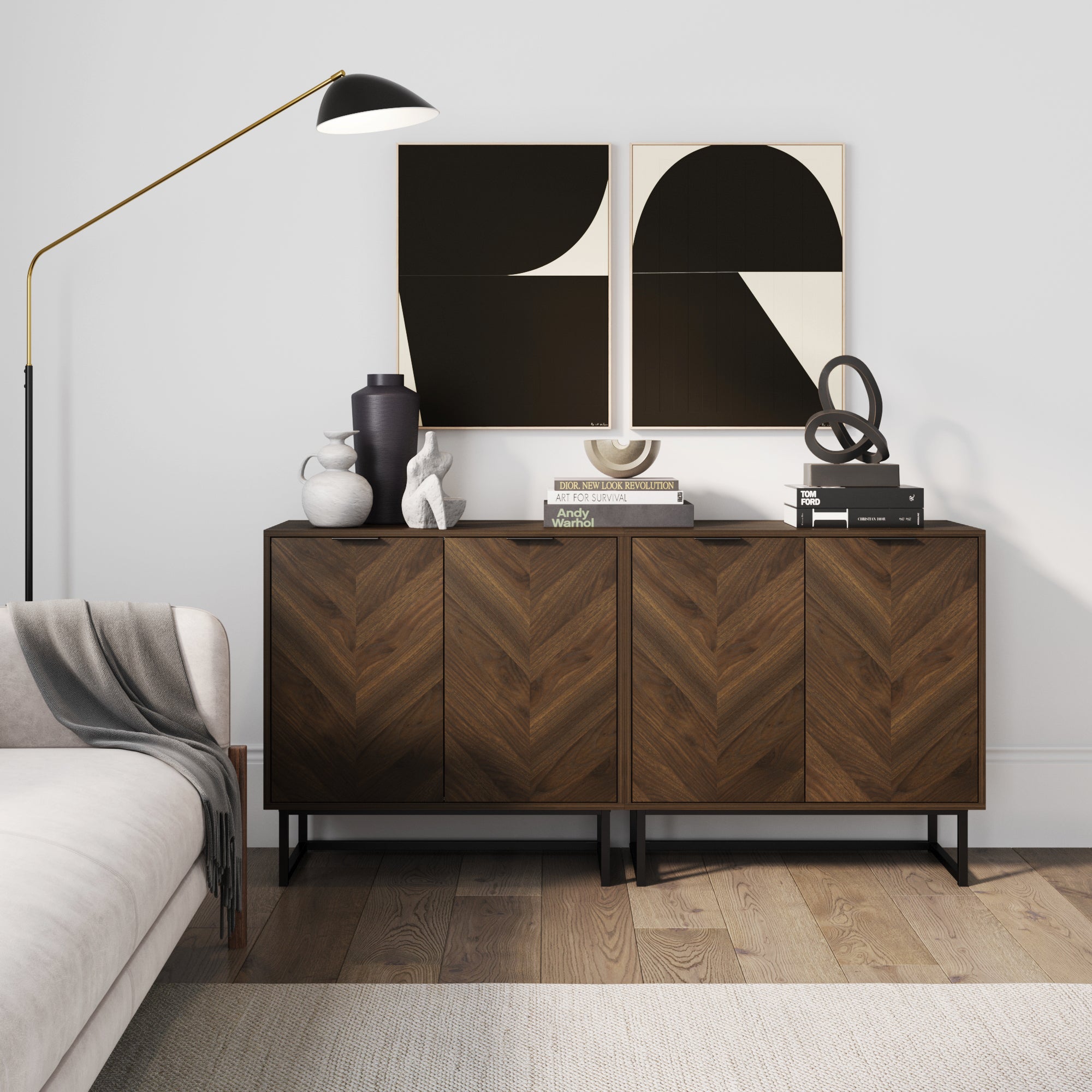 A modern living room features a wood sideboard with a chevron pattern, abstract black-and-white art above, decorative vases, books, and a sculpture on top, next to a sofa and a tall floor lamp.
