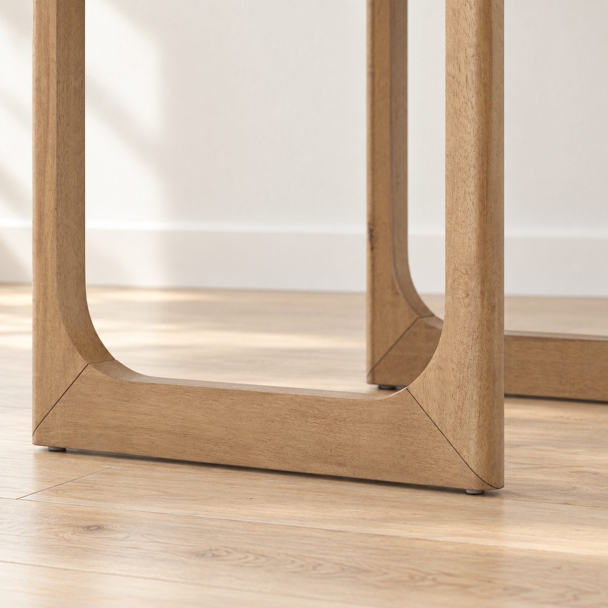 Close-up of the light wood legs of a table, featuring a curved, U-shaped base resting on a wooden floor.