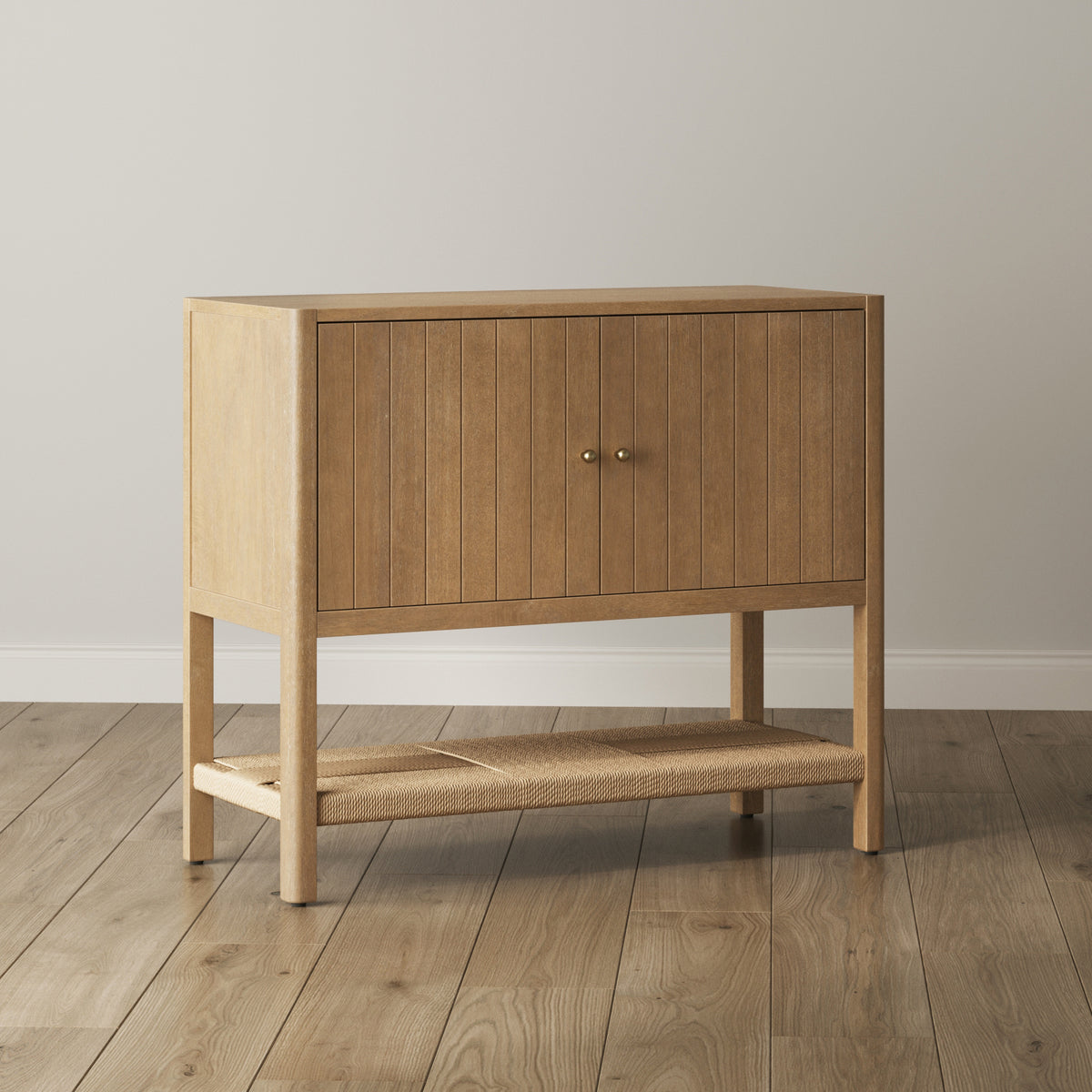 Light wood cabinet with two doors featuring vertical slats and a lower woven shelf.