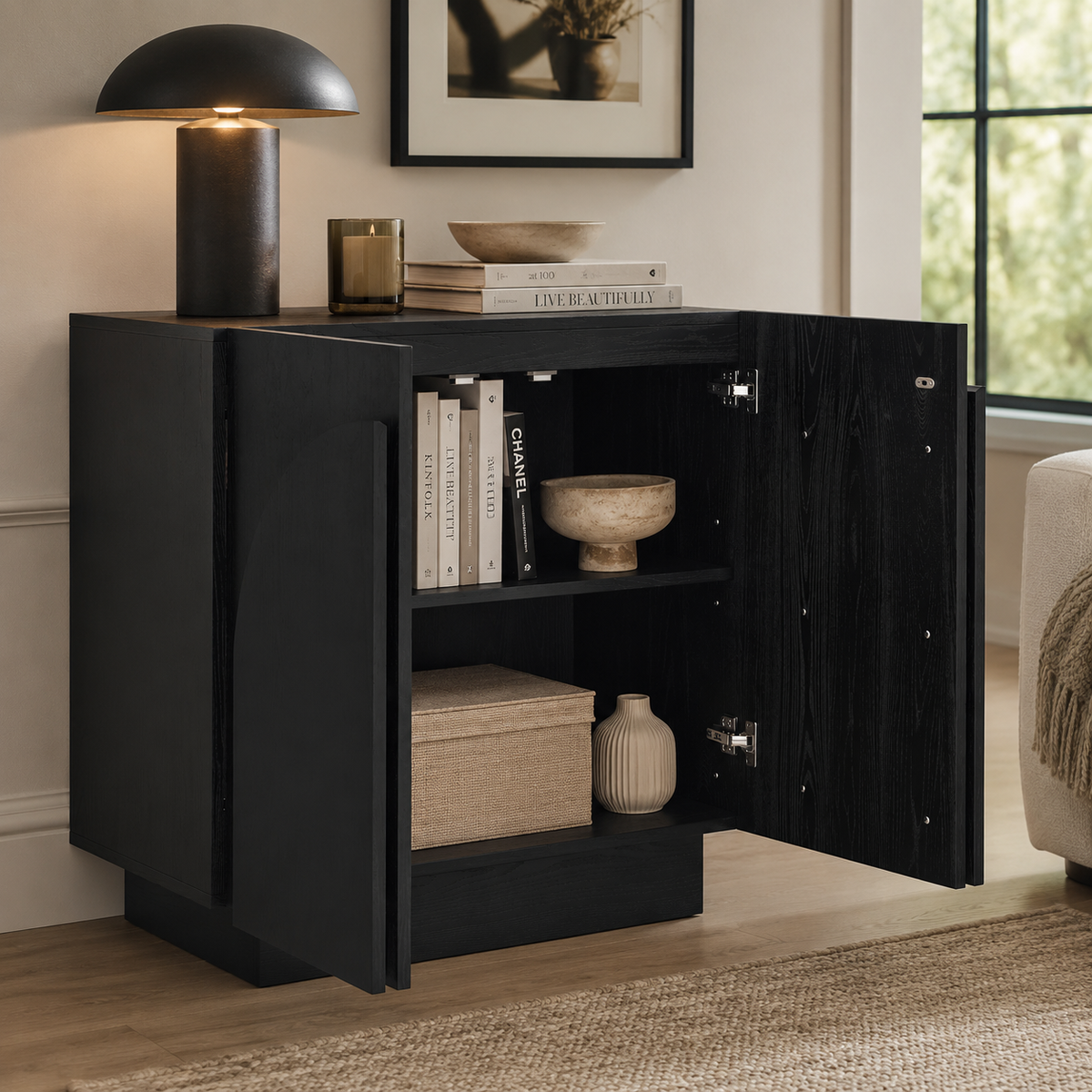 Black wooden cabinet with open doors, displaying books and decorative bowls on its interior shelves.